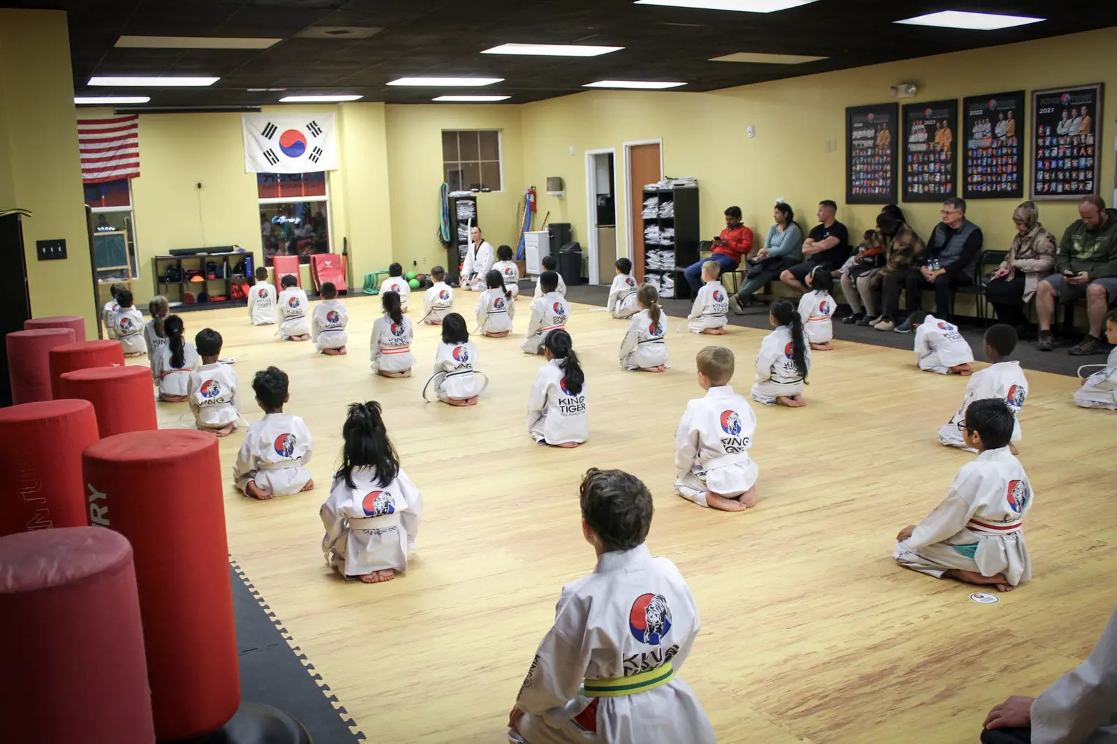 A full King Tiger youth class with families observing from the studio
