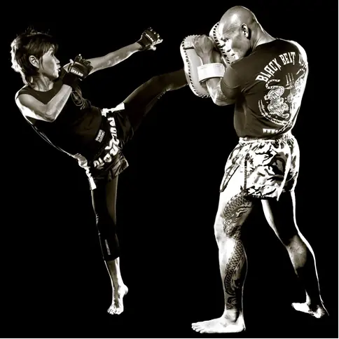 Muay Thai athletes practicing a controlled kick and pad drill